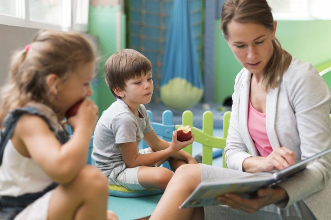 medium-shot-teacher-reading-to-kids-min Escuela infantil en Valencia en Inglés